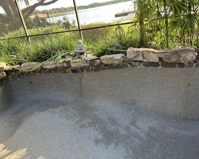Rectangular pool with a raised spa and travertine deck on weekly service